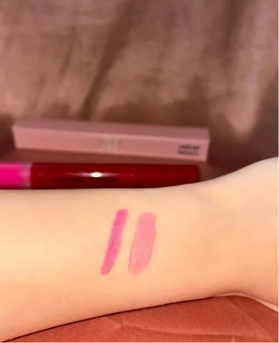 Pink lip gloss swatched on a wrist with a blurred background