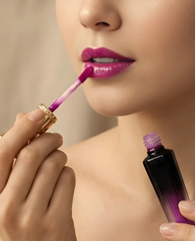 Close-up of a person applying purple lipstick with a matching lip gloss.