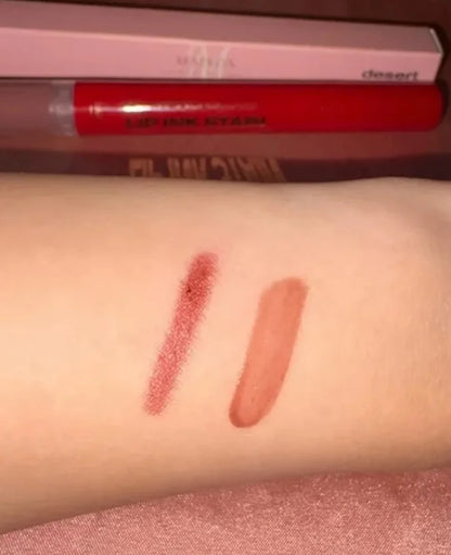 Two lip color swatches applied on a person's forearm, with a red lip tint tube and a pink box visible in the background. The swatches show a matte dusty rose-red shade and a glossy warm nude-peach shade.